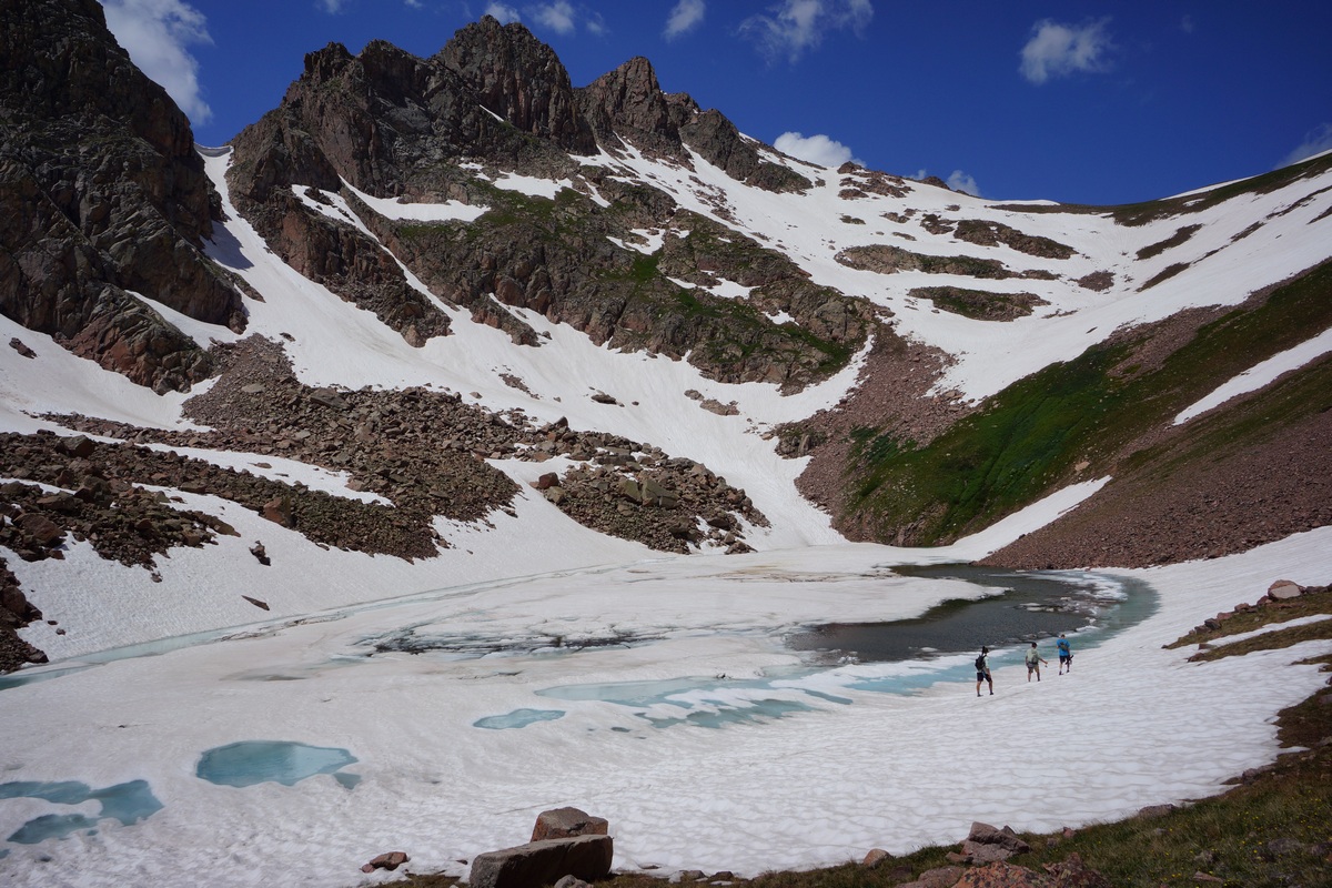 3 hikers walking around snow lake in july - gore mountains, colorado