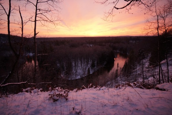 pink sky sunrise in winter over manistee river in michigan